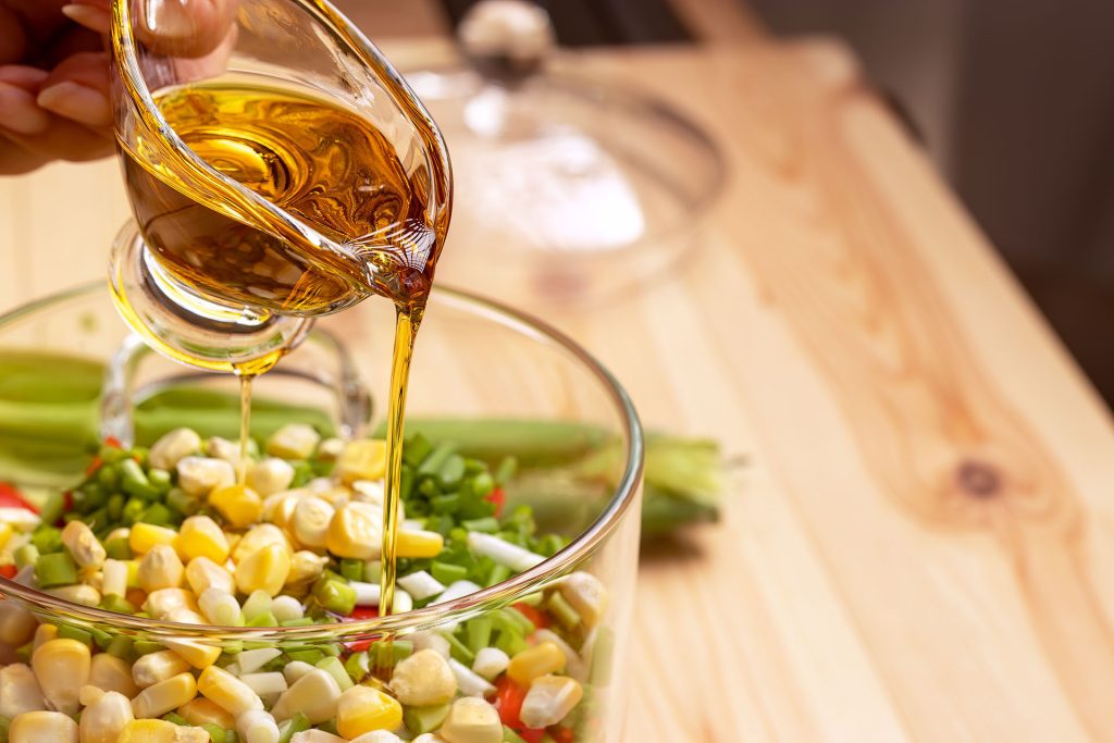 cvoils-landing-page Columbus Vegetable Oil being poured into a container of vegetables.