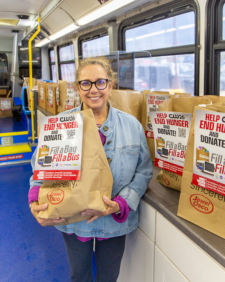 Woman holding a bag on a bud that reads, "Help end hunger and donate. Fill a bag, fill a bus."