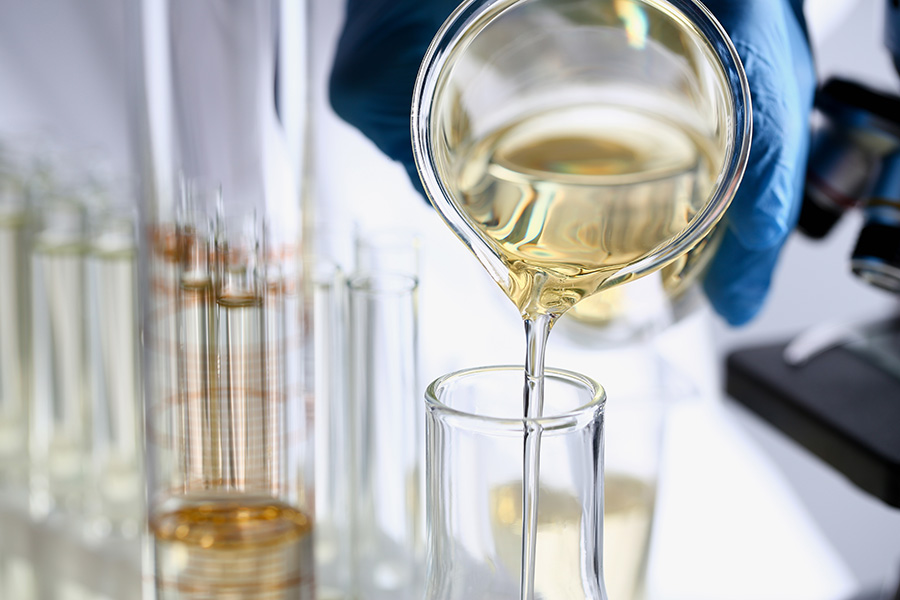 Person in a lab pouring oil into a beaker