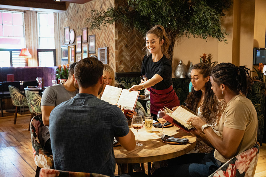 Woman offering a table menu's in a restaurant setting