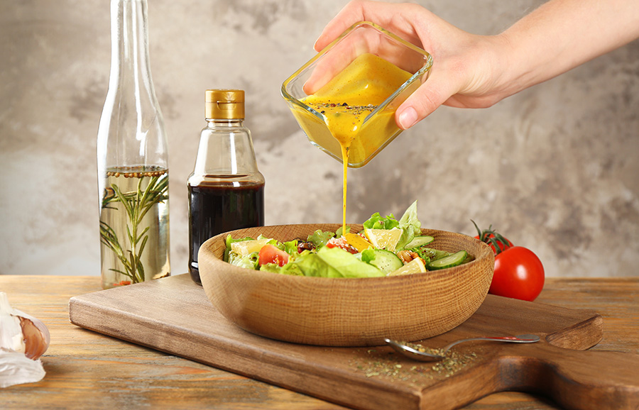 Yellow sauce being poured onto a salad