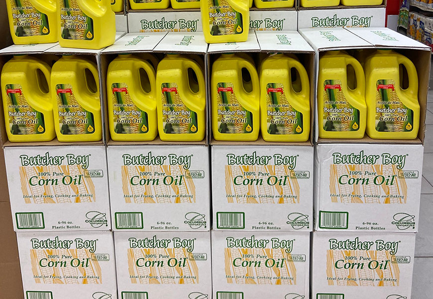 Multiple Butcher Boy branded 100% pure corn oil boxes and containers inside a store setting.